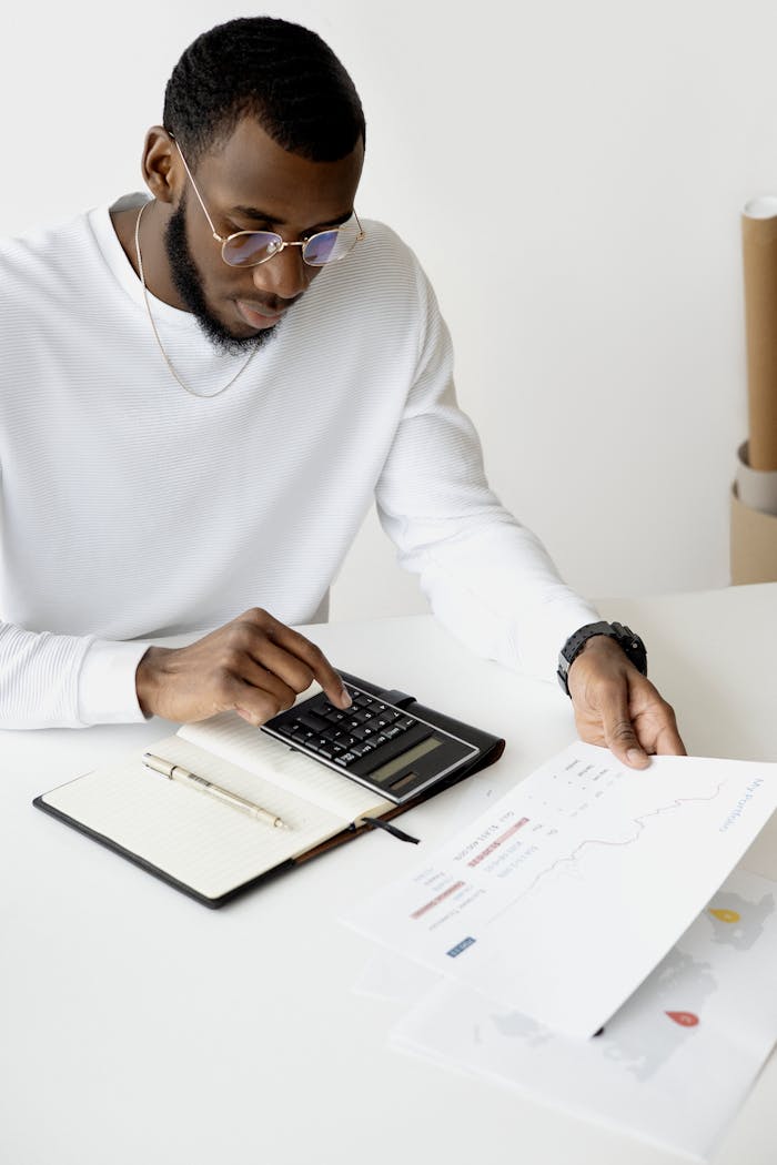 Professional analyzing documents and using a calculator at an office desk.